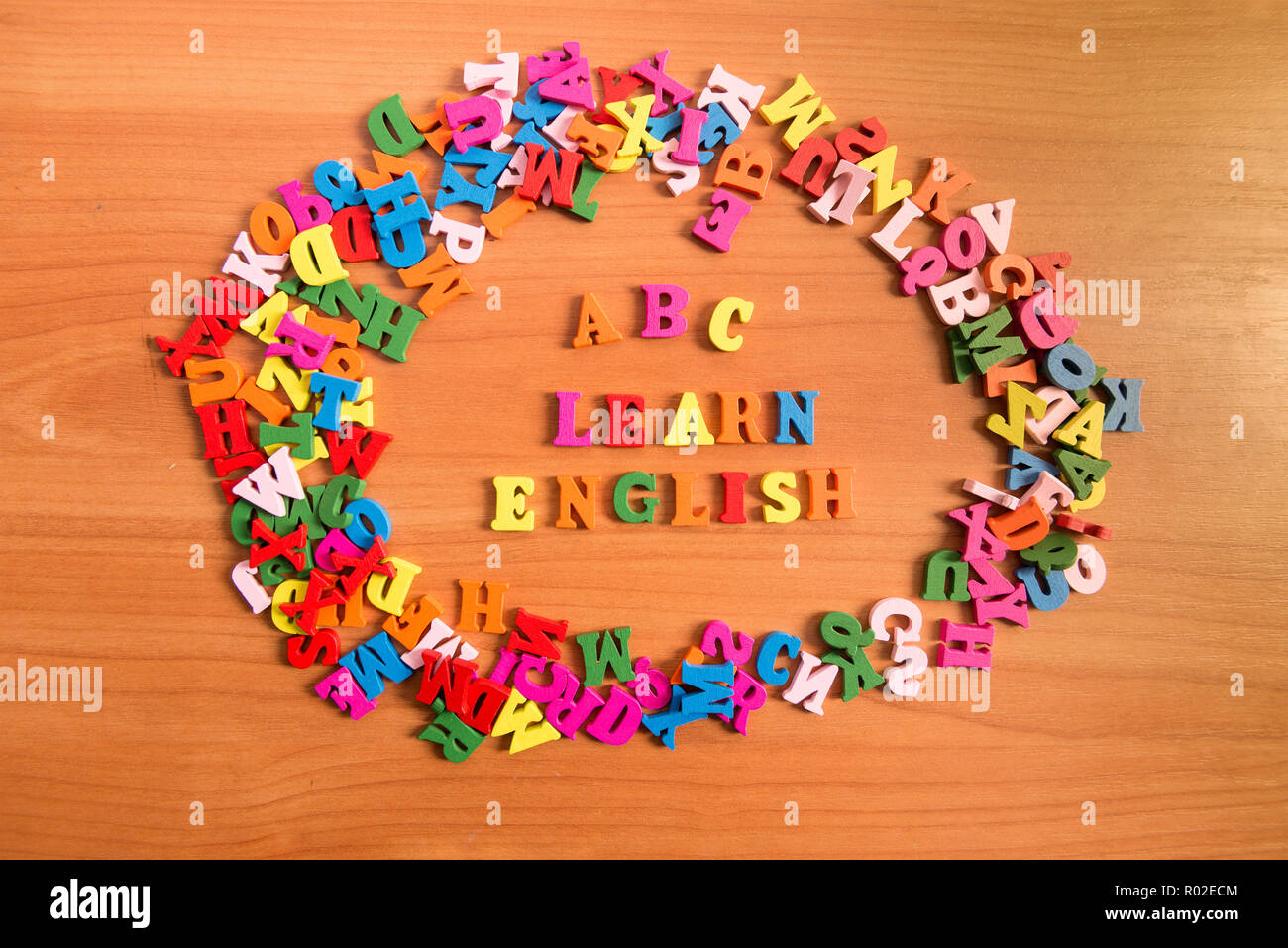 ABC LEARN ENGLISH wooden letters around a pile of other letters over table board surface Stock Photo