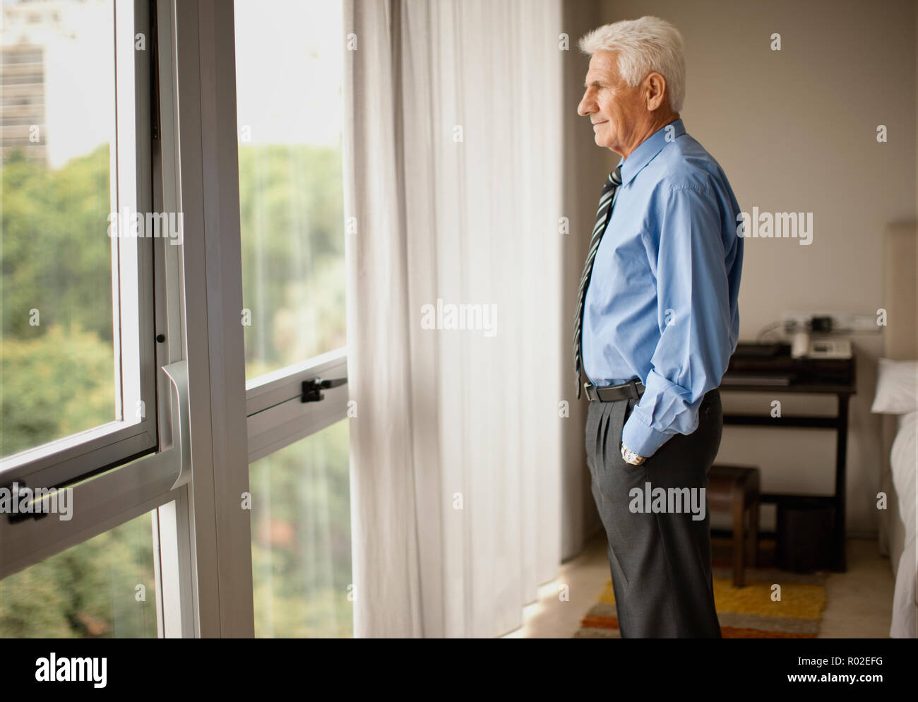 Senior businessman at home,  looking out window. Stock Photo