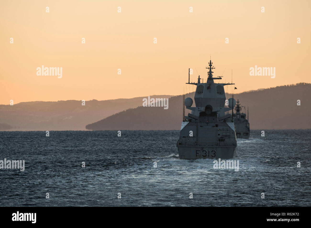 Her Majesty’s Canadian Ship (HMCS) VILLE DE QUÉBEC follows His Norwegian Majesty’s Ship HELGE INGSTAD and other NATO warships into The Trondheim Fjord at sunrise during Exercise TRIDENT JUNCTURE on October 29, 2018.    Photo: MCpl Andre Maillet, MARPAC Imaging Services Stock Photo