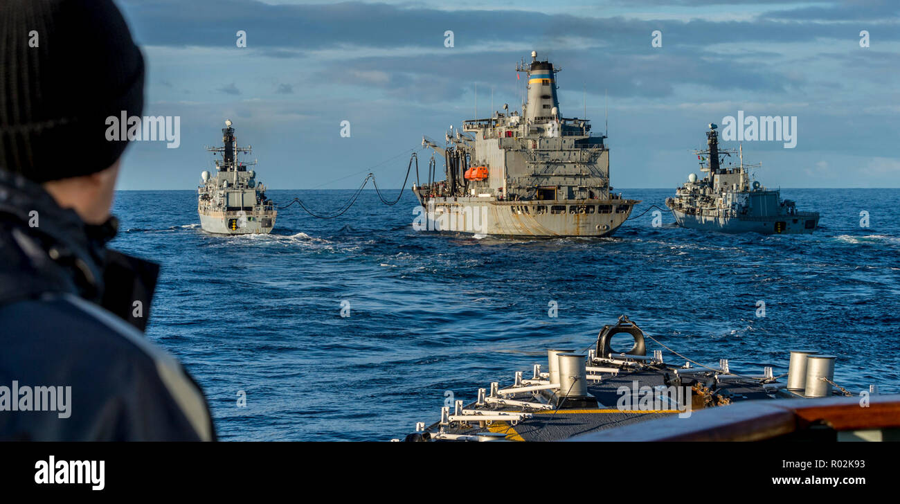 Her Majesty's Canadian Ship (HMCS) HALIFAX awaits its turn for Replenishment at Sea (RAS) with United States Naval Ship (USNS) LEROY GRUMMAN (Centre) during TRIDENT JUNCTURE 2018, off the coast of Norway, Norwegian Sea, on October 28th, 2018.    Visible in Photo: Her Majesty's Ship (HMS) NORTHUMBERLAND (Left) and HMS WESTMINSTER (Right).    Photo Credit: Able Seaman (AB) John Iglesias  Formation Imaging Services, HMCS HALIFAX, Imagery Technician © 2018 DND-MDN Canada  Original Image Name: HS17-2018-0933-847 Stock Photo