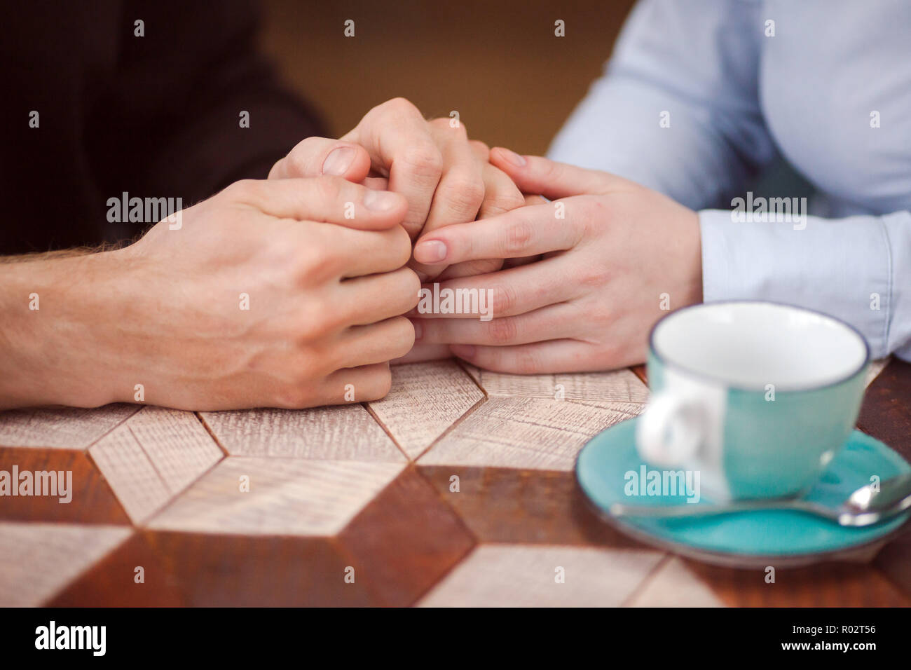 Crop loving couple holding hands at table Stock Photo