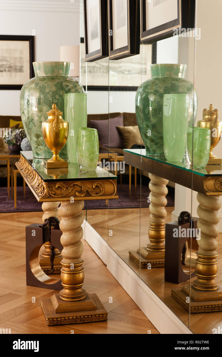 Vases on gold table by mirrored wall Stock Photo