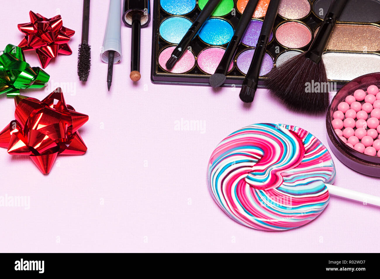 Bright makeup for birthday party. Color glitter eyeshadow, blush, liquid  eyeliner, mascara, make up brushes with lollipop and gift wrap bows. Copy  spa Stock Photo - Alamy