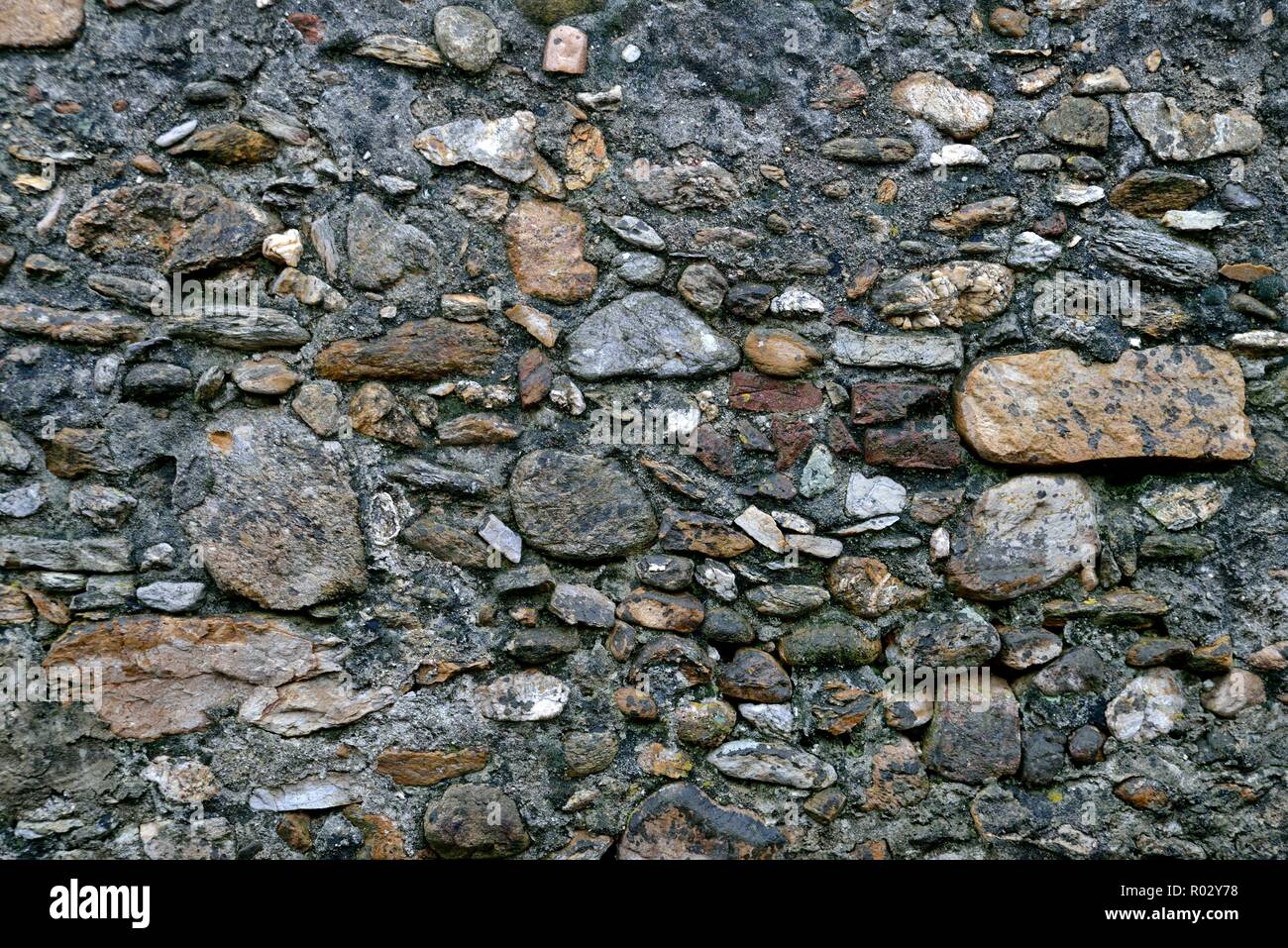 Weathered old stone wall background black gray Stock Photo