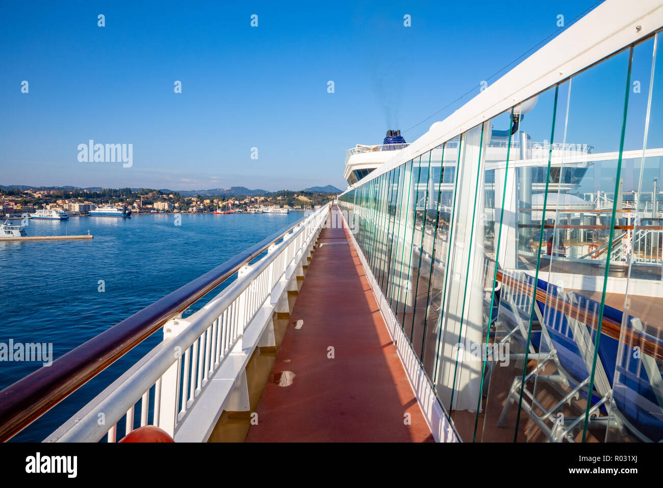 Perspective view of outdoor steel deck at a cruise ship with sea and town in the background Stock Photo