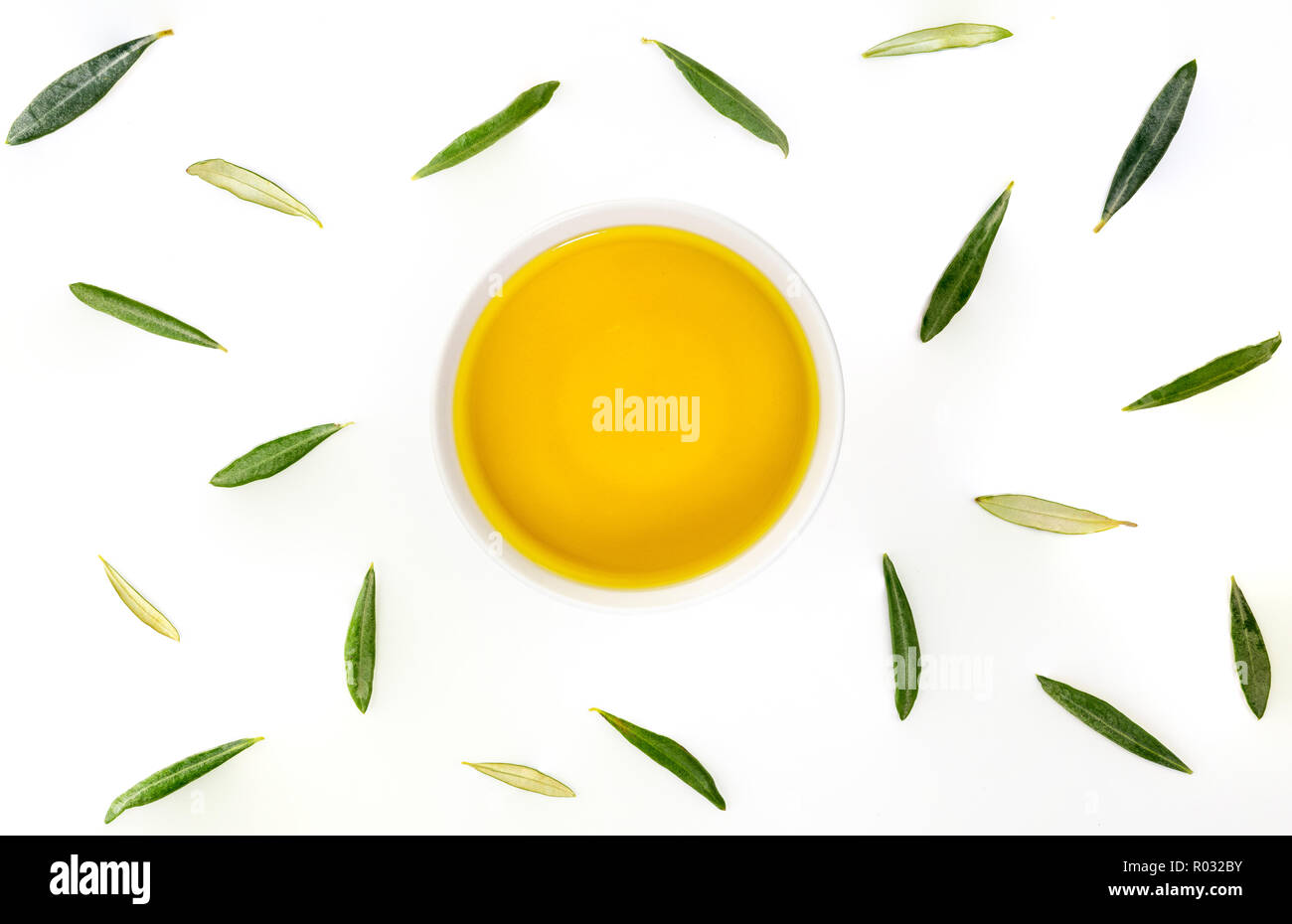Bowl of extra virgin olive oil with olive leaves. Zenital plane on white background. Stock Photo