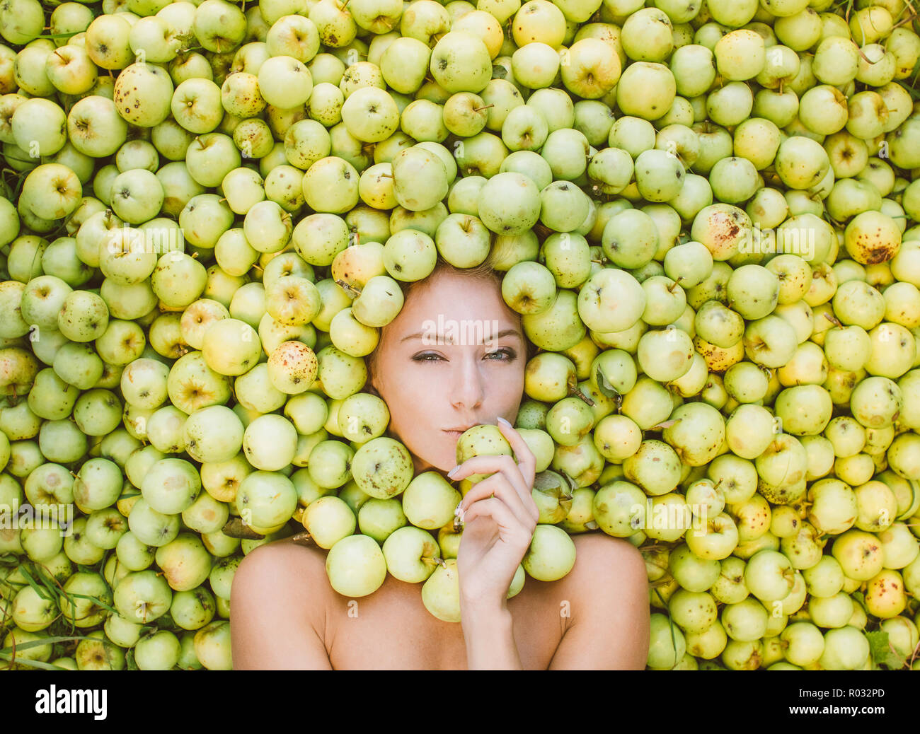 Portrait of beautiful girl that lies in the green apples, apples near the face, kissing apple Stock Photo