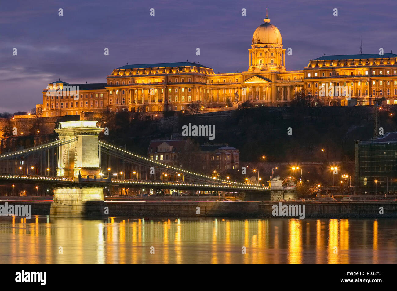 Chain Bridge and Royal Palace reflected in River Danube illuminated at dusk, Budapest, Hungary Stock Photo