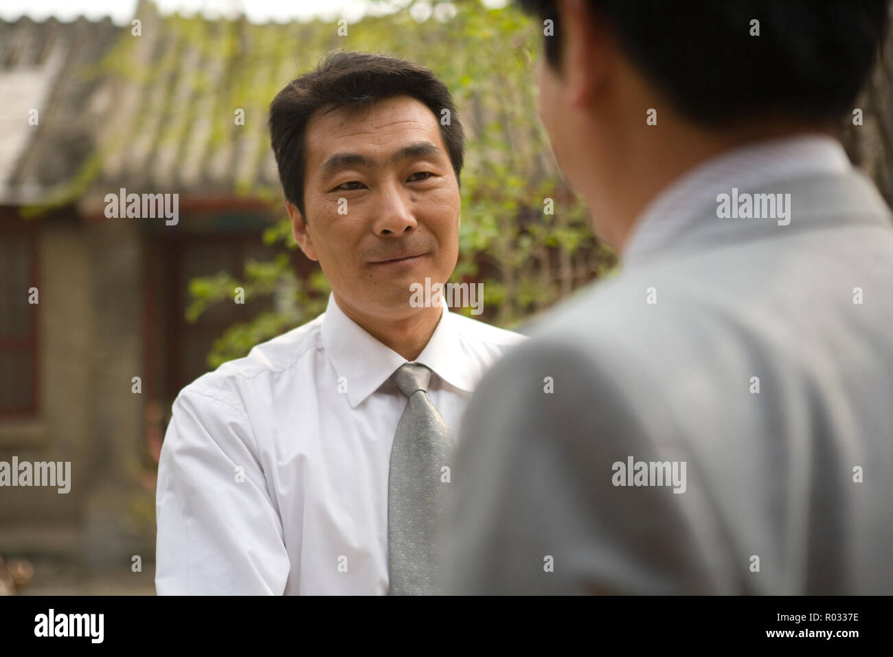 Mid-adult businessman greeting a colleague outside a building. Stock Photo