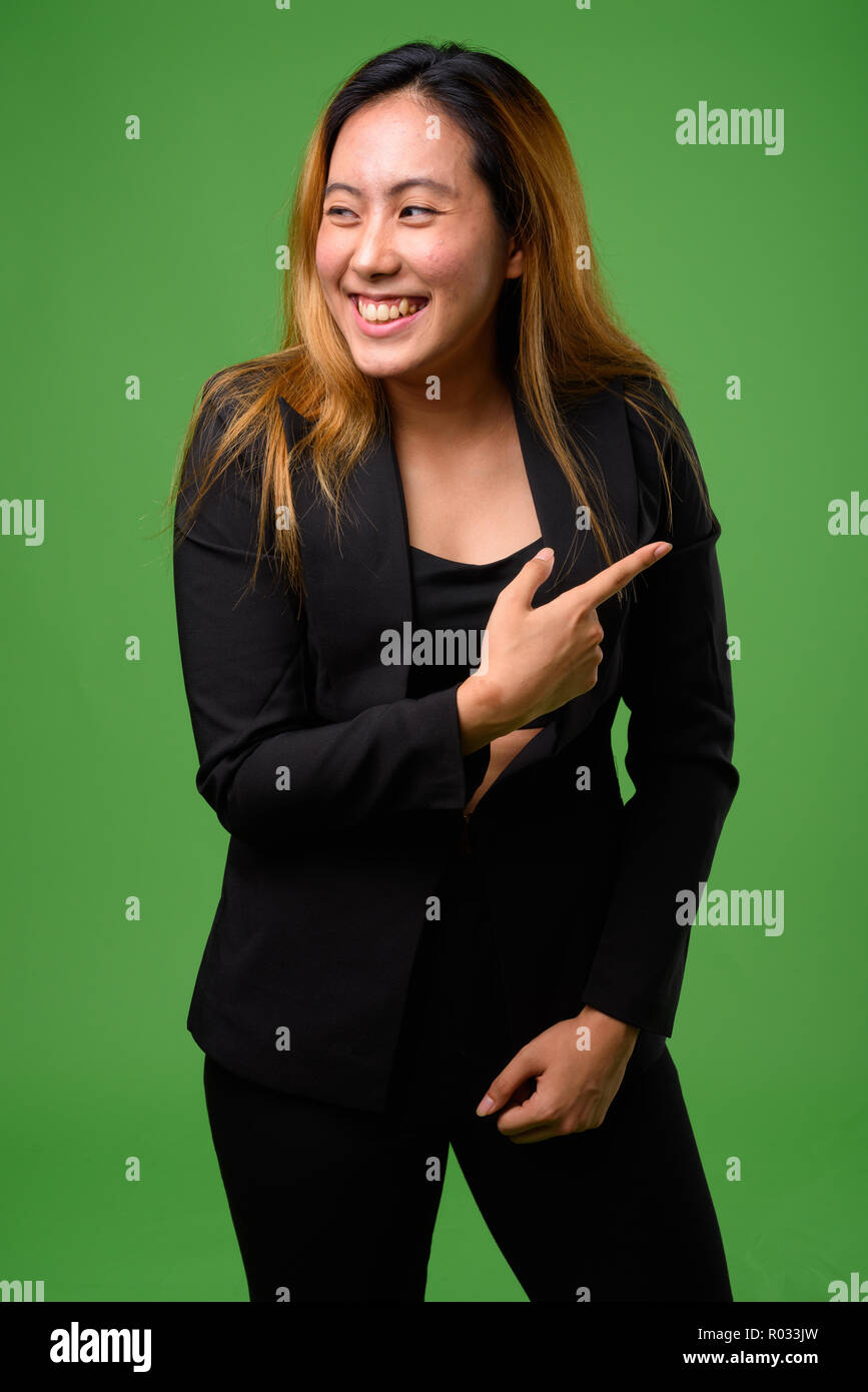 Portrait of young Asian businesswoman against green background Stock Photo