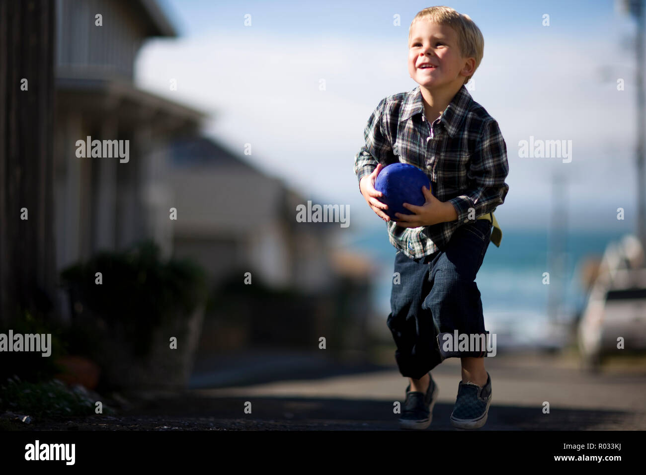 Young boy playing outside with a toy football. Stock Photo