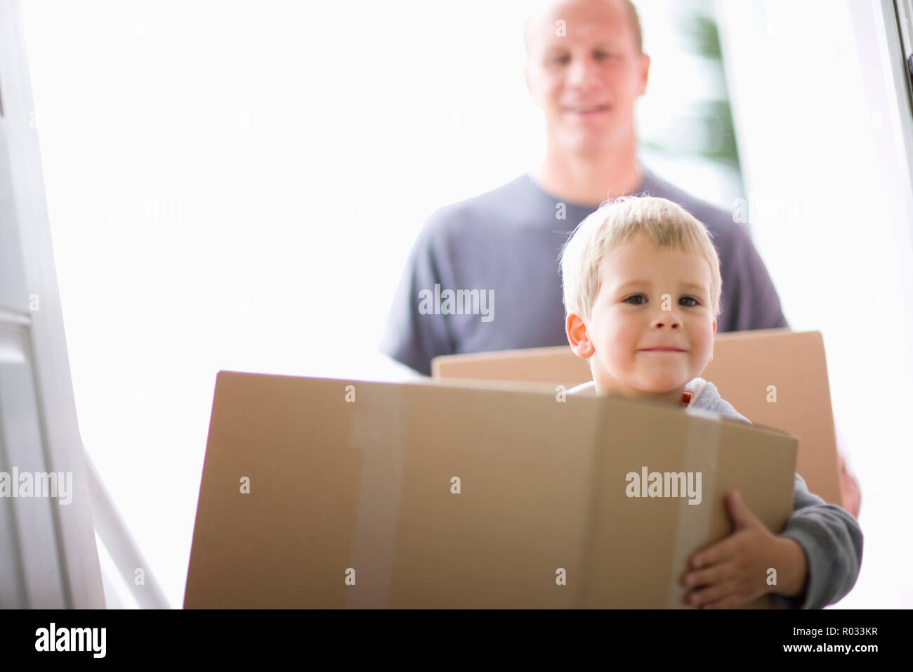 Portrait of a young boy and his mid-adult father hugging in a house. Stock Photo