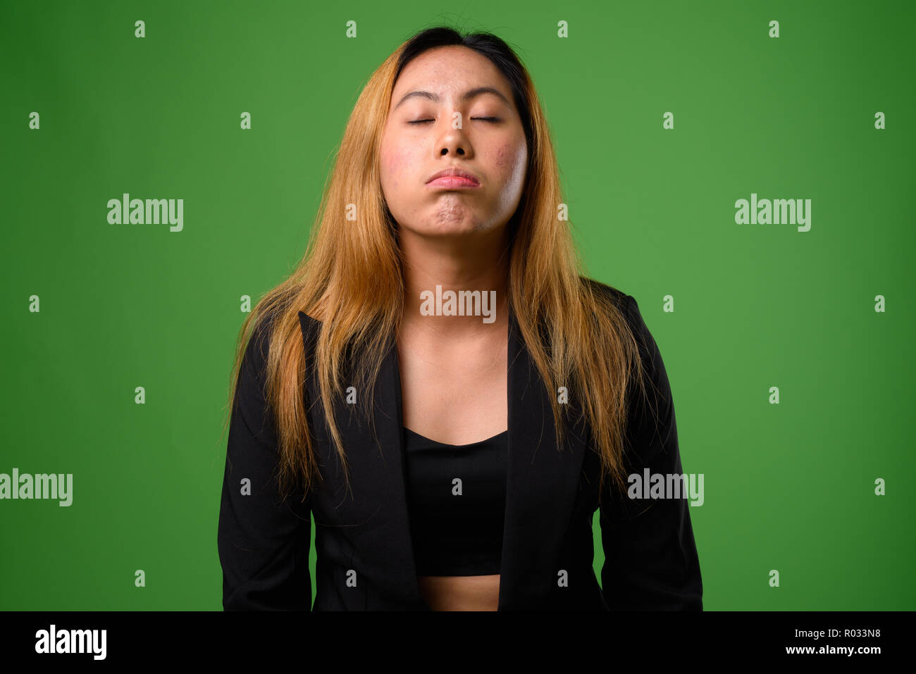 Portrait of young Asian businesswoman against green background Stock Photo