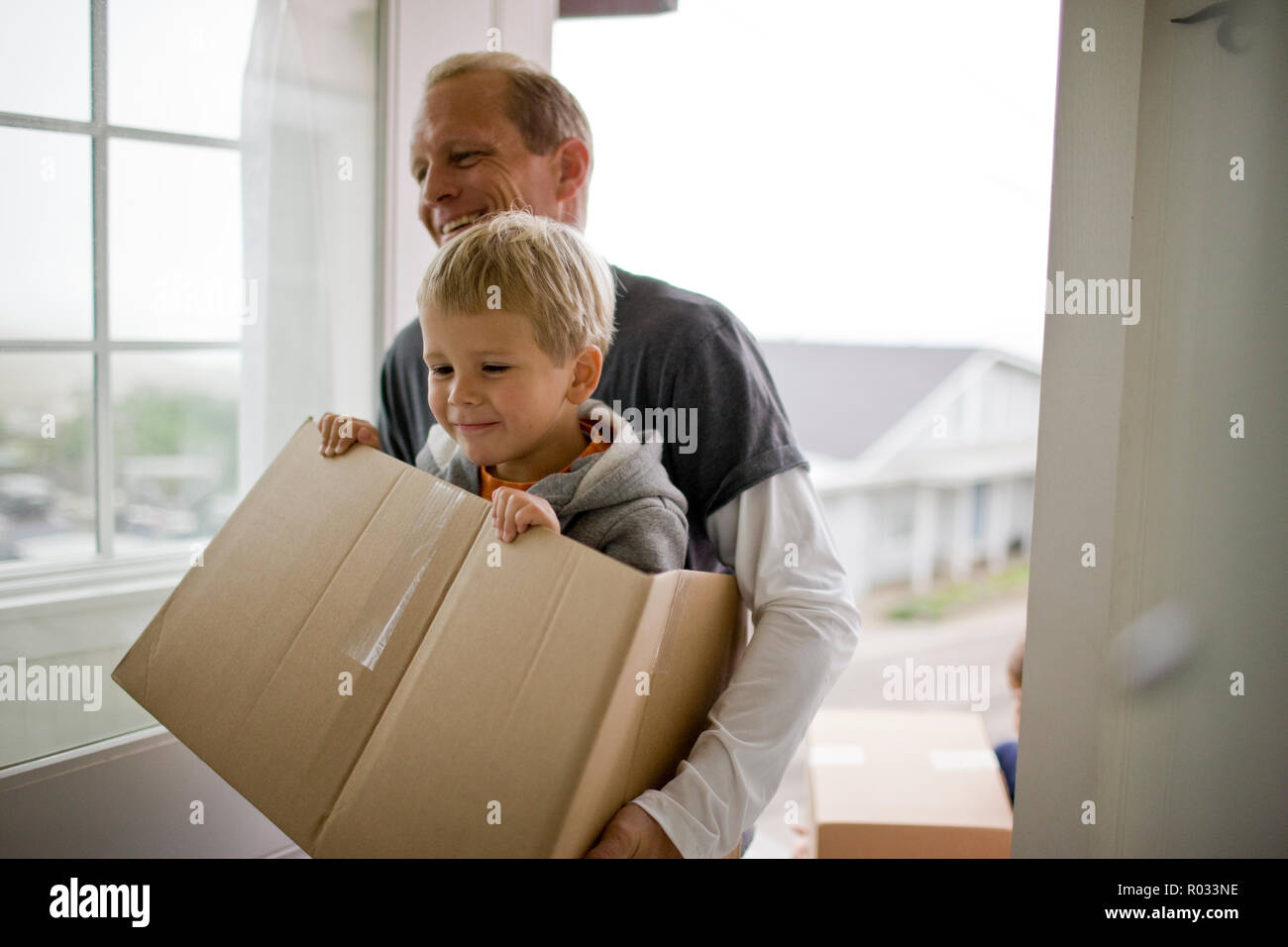 Father carrying son in box while moving house Stock Photo