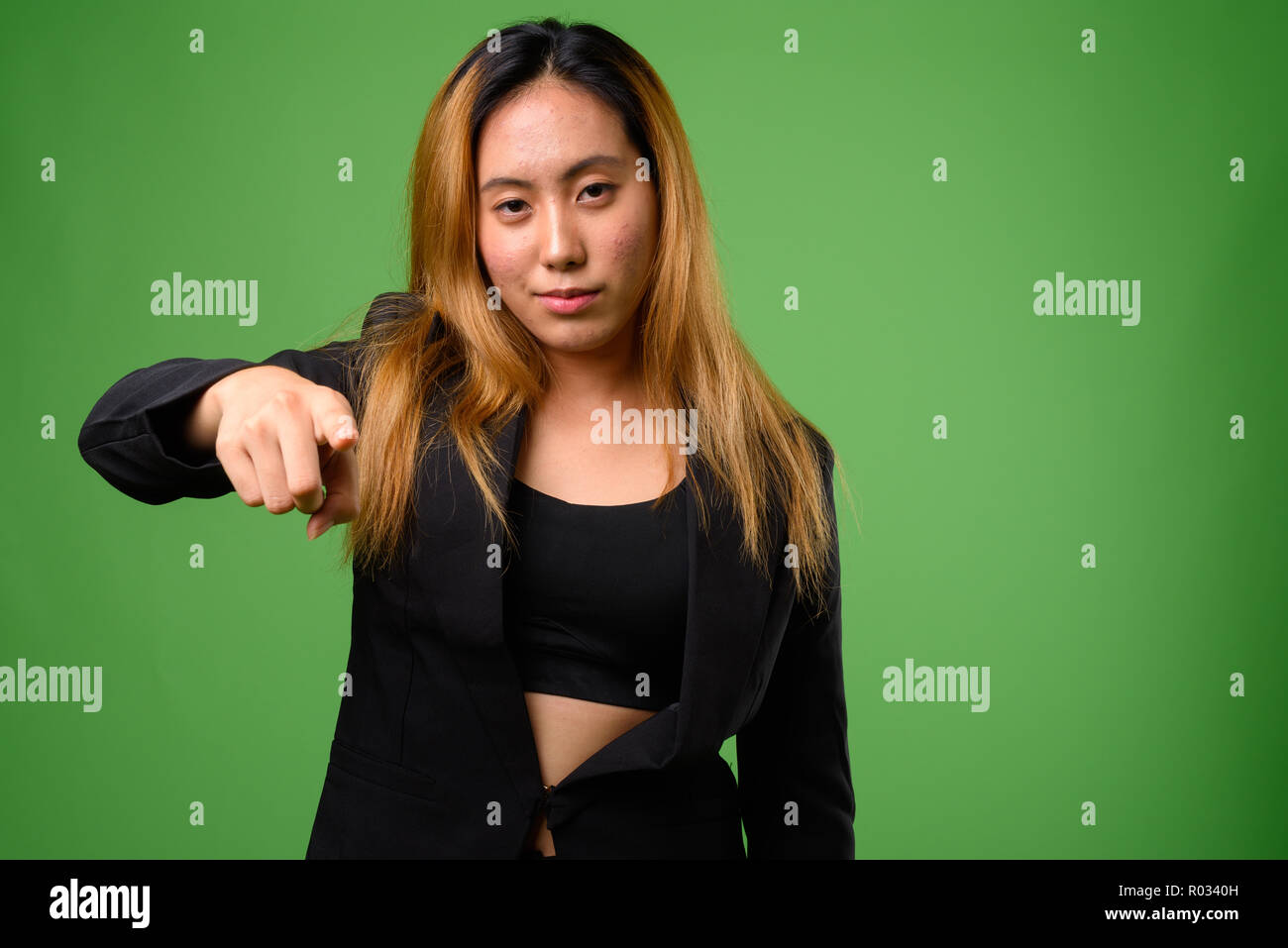 Portrait of young Asian businesswoman against green background Stock Photo
