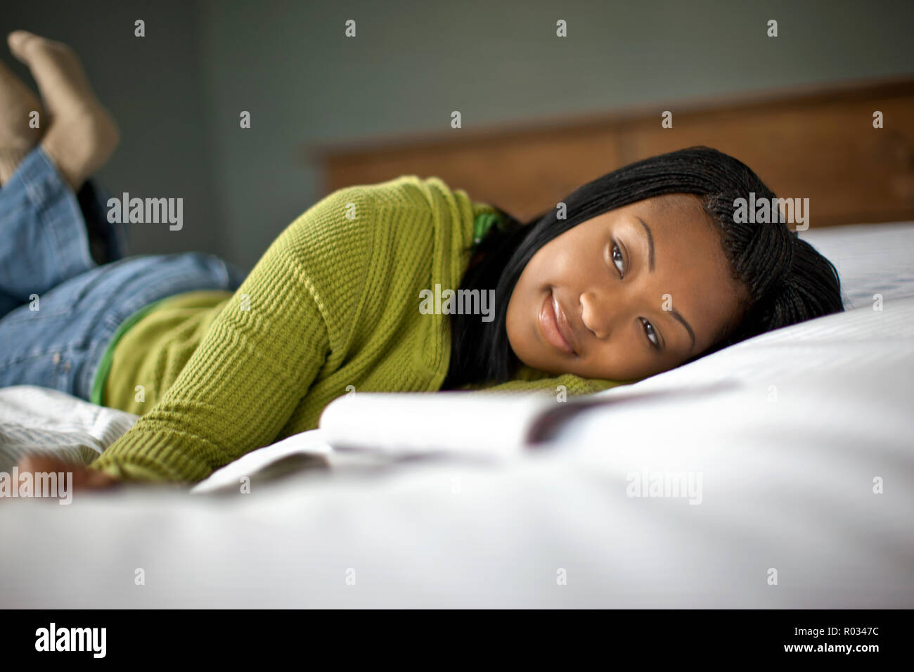 Happy teenage girl relaxing on her bed. Stock Photo