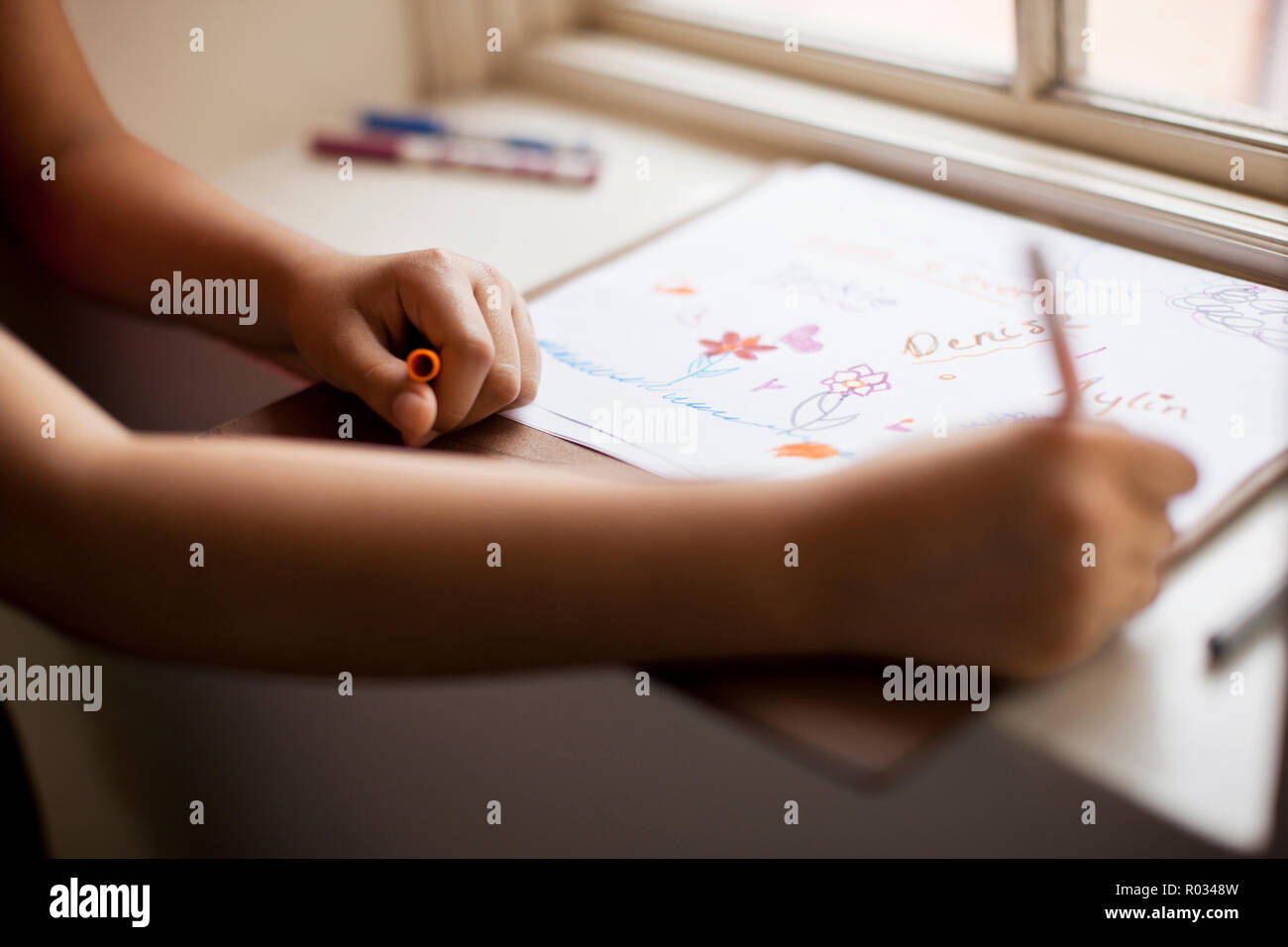 Hands on a school girl coloring in a book. Stock Photo