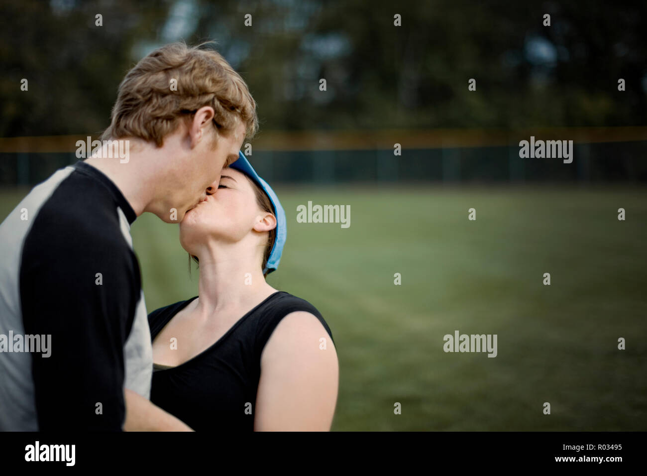 Young adult couple kissing near a sports field. Stock Photo