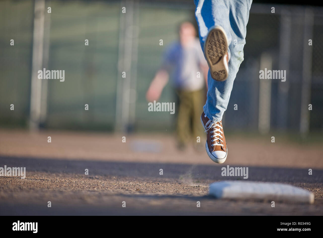 Teenage boy's sneakers leaping towards a baseball mat. Stock Photo