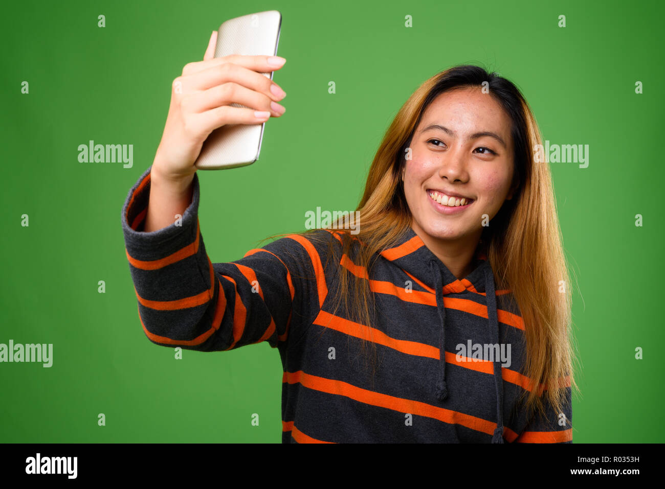 Portrait of young Asian woman against green background Stock Photo - Alamy