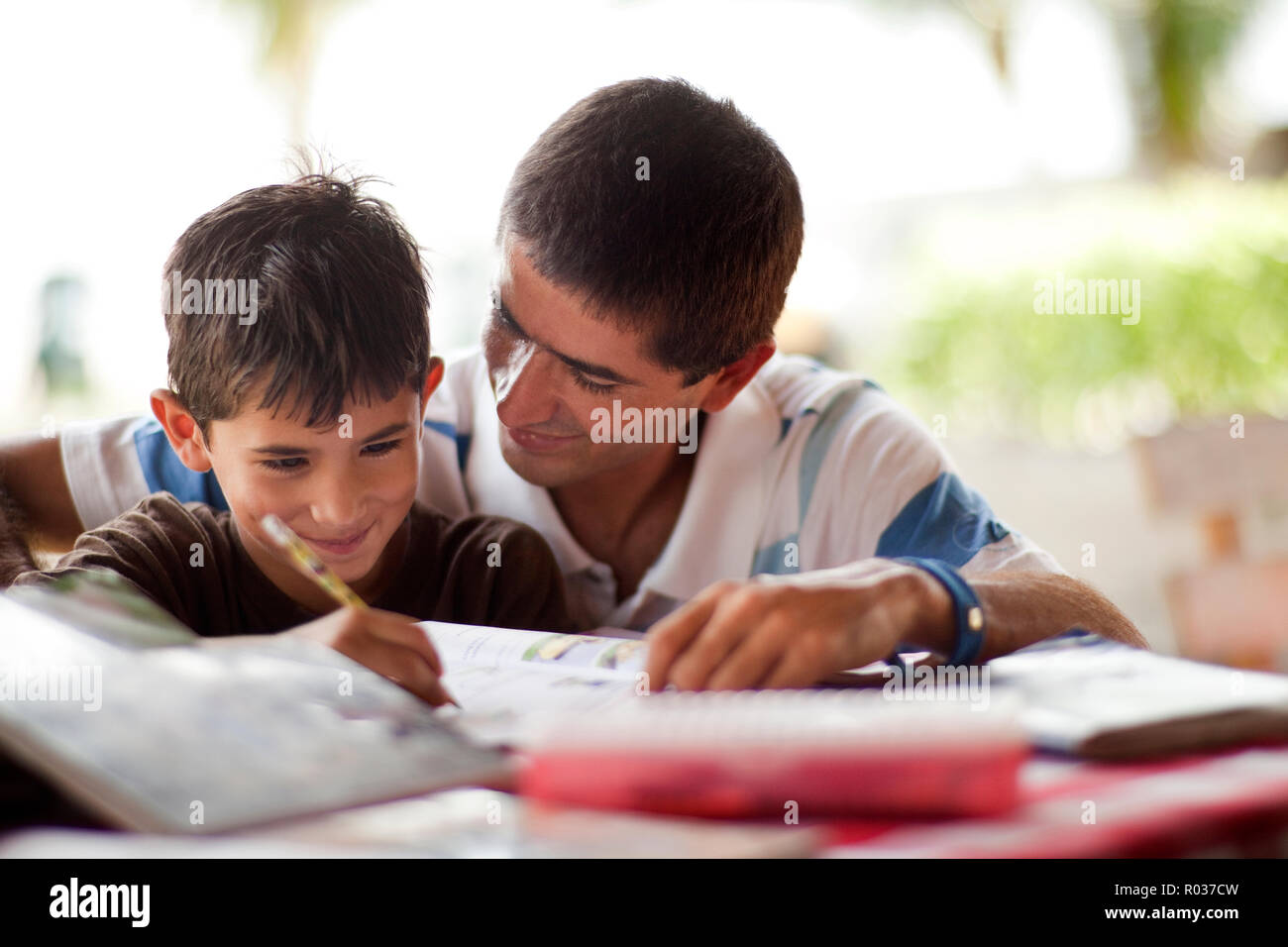 Father helping his son with his homework on a table. Stock Photo