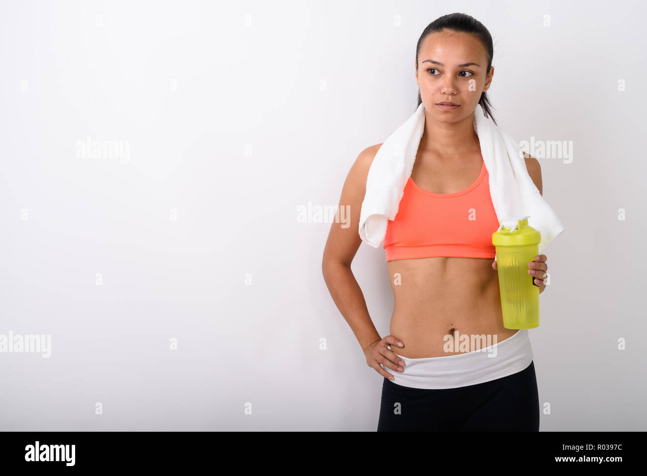 Studio shot of young Asian woman thinking while holding water bo Stock Photo