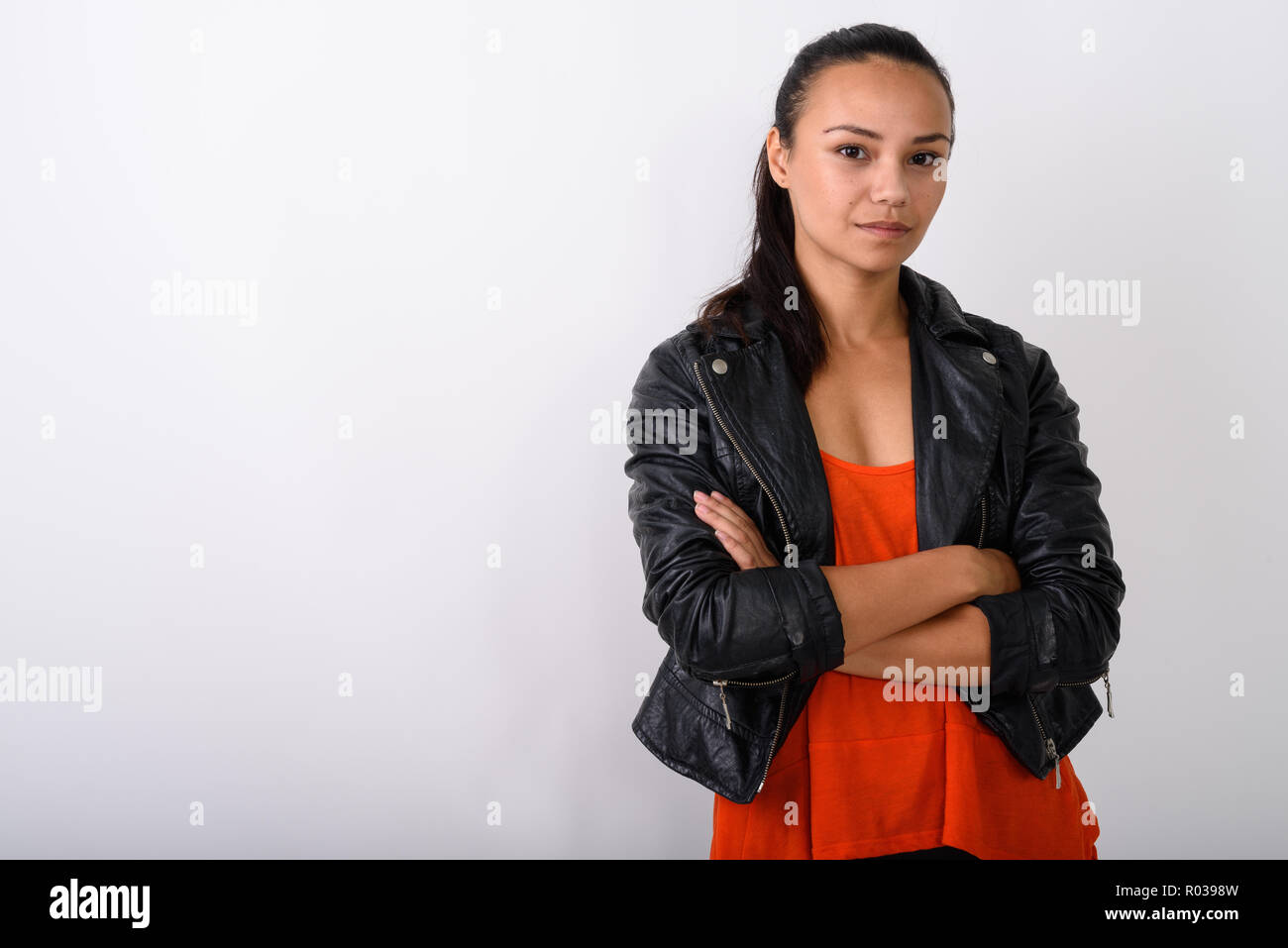 Studio shot of young Asian woman wearing leather jacket with arm Stock Photo