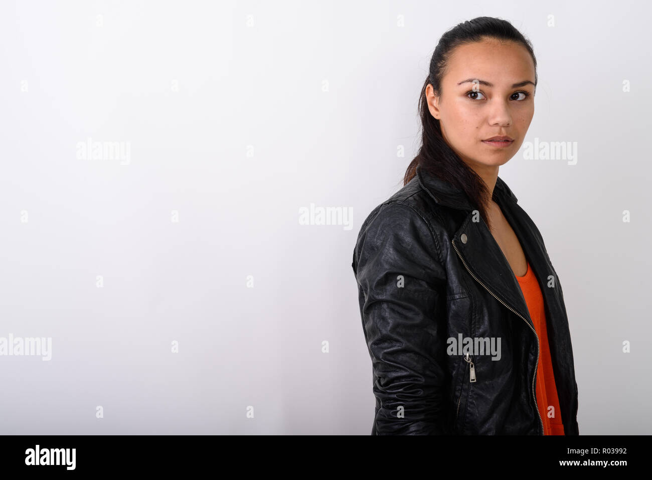 Studio shot of young Asian woman thinking while wearing leather  Stock Photo