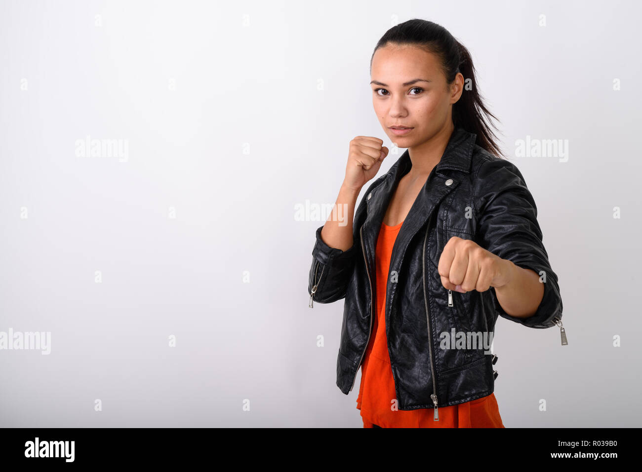 Studio shot of young Asian woman wearing leather jacket ready to Stock Photo