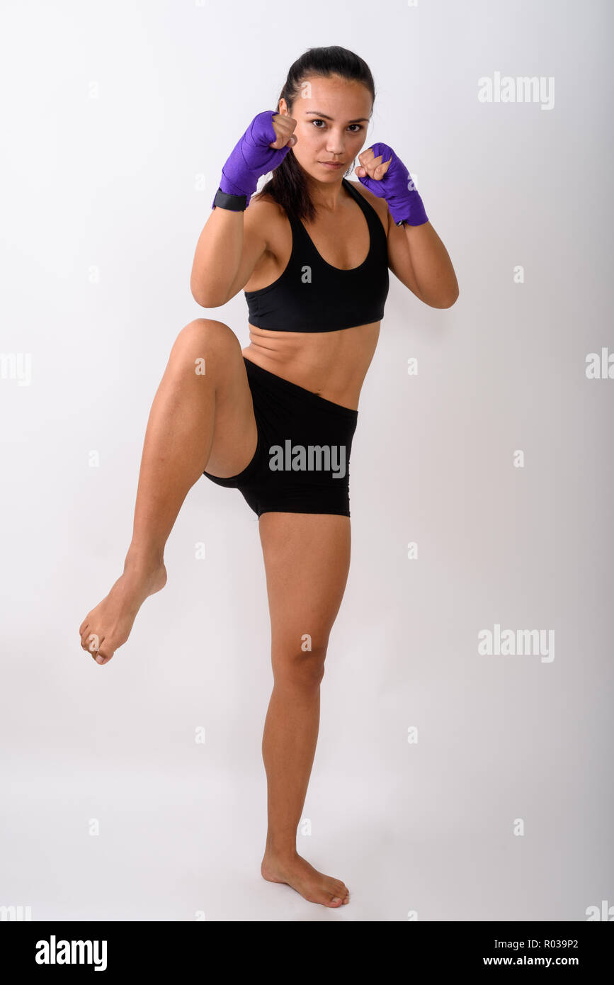 Full body shot of young Asian woman fighter with leg raised read Stock Photo