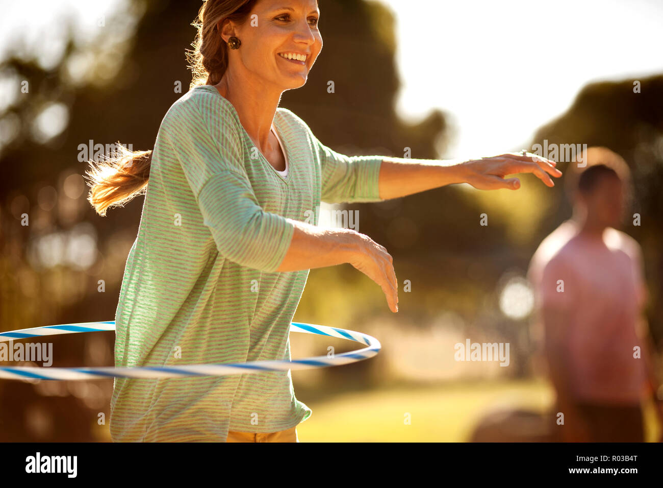 Mid adult woman using a hula hoop while at a park. Stock Photo