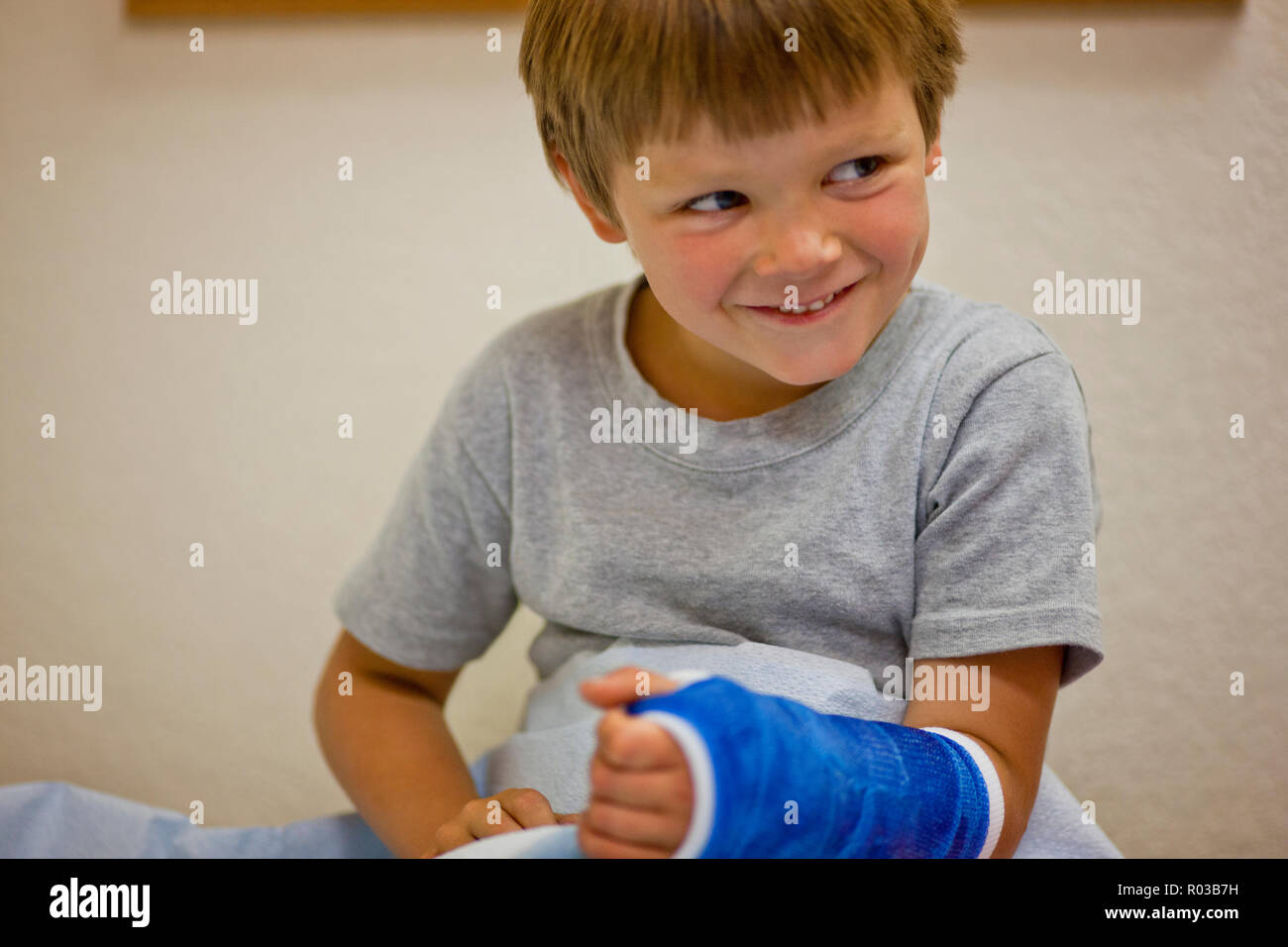 Young boy with a cast on his arm sitting in a doctor's office. Stock Photo