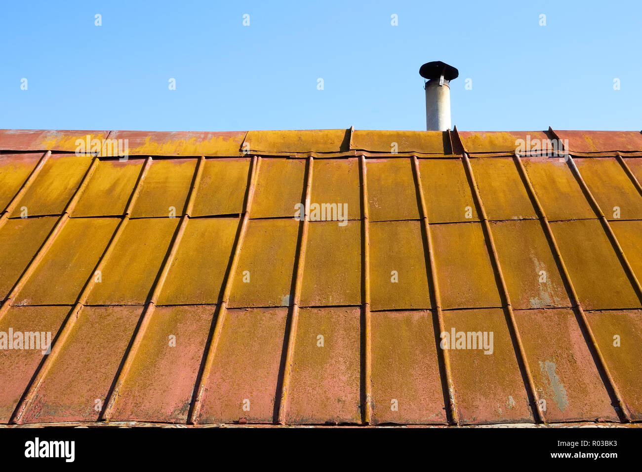 Detail of the roof covered with old metal painted tile Stock Photo