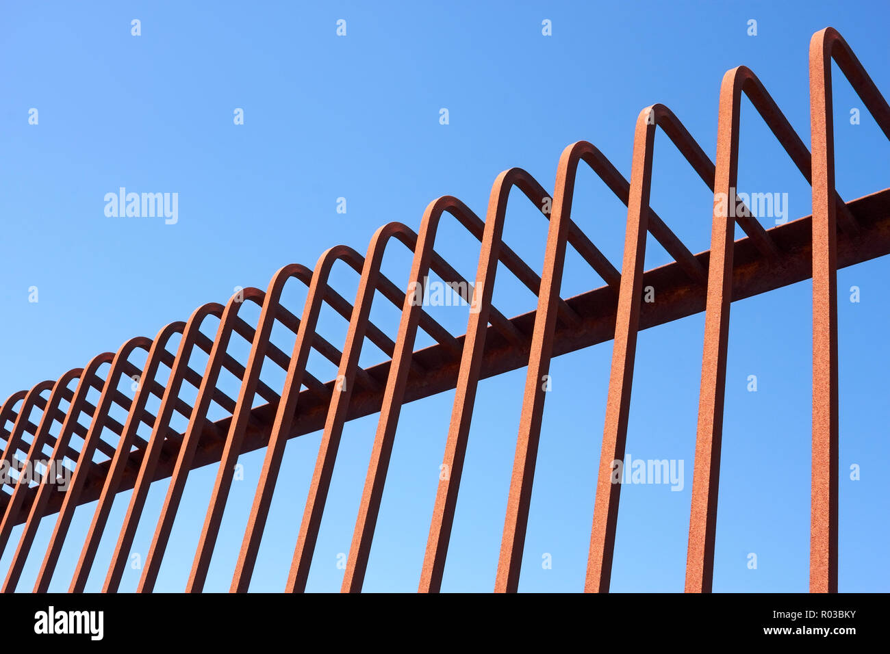 Detail of fence with bent metal rods against a blue sky Stock Photo