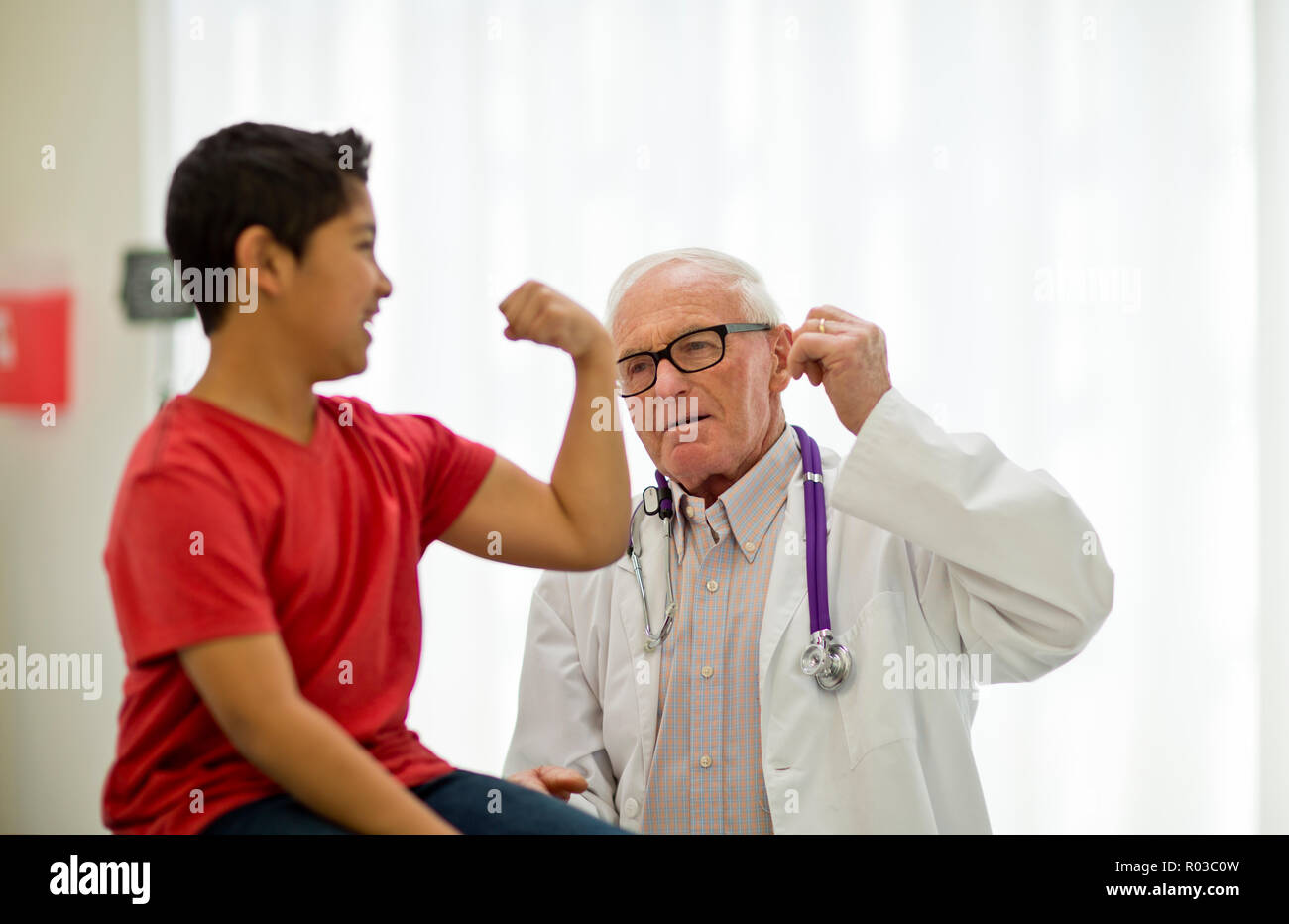Playful young boy flexing his muscles at a doctor's office. Stock Photo
