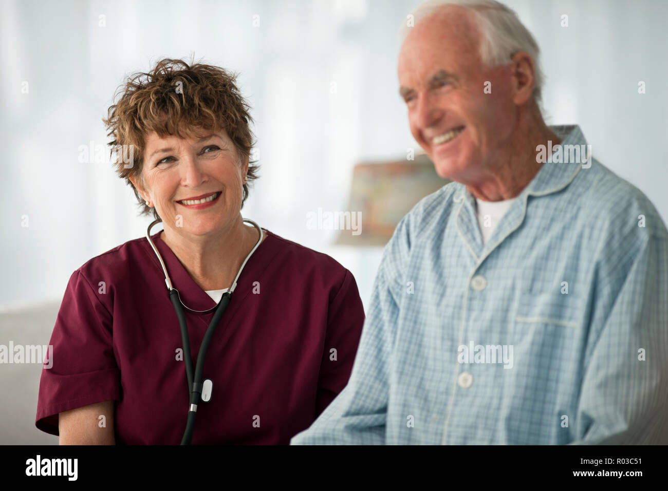 Smiling mature nurse sitting with an elderly patient. Stock Photo