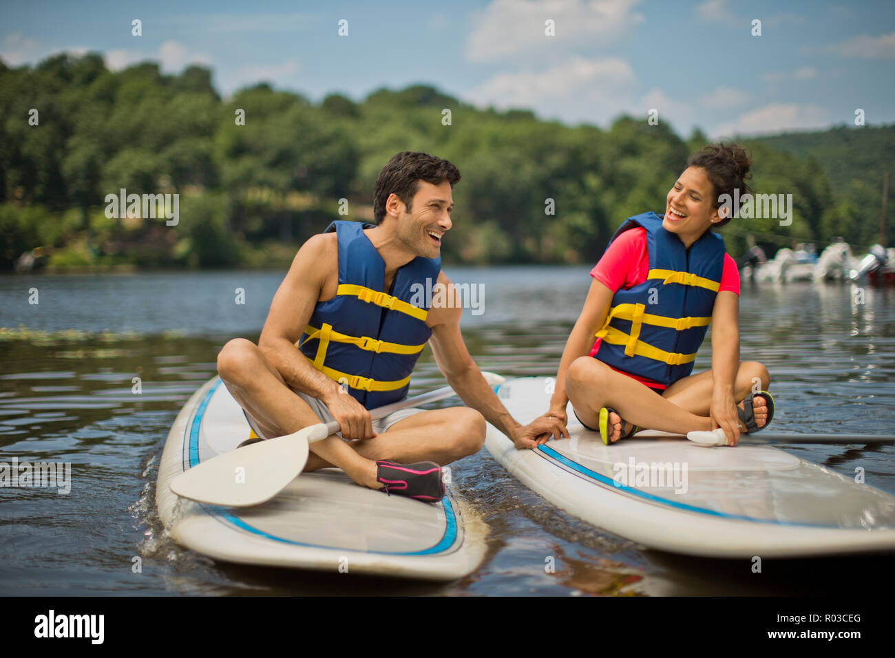 Young couple playfully flirting on paddleboards. Stock Photo