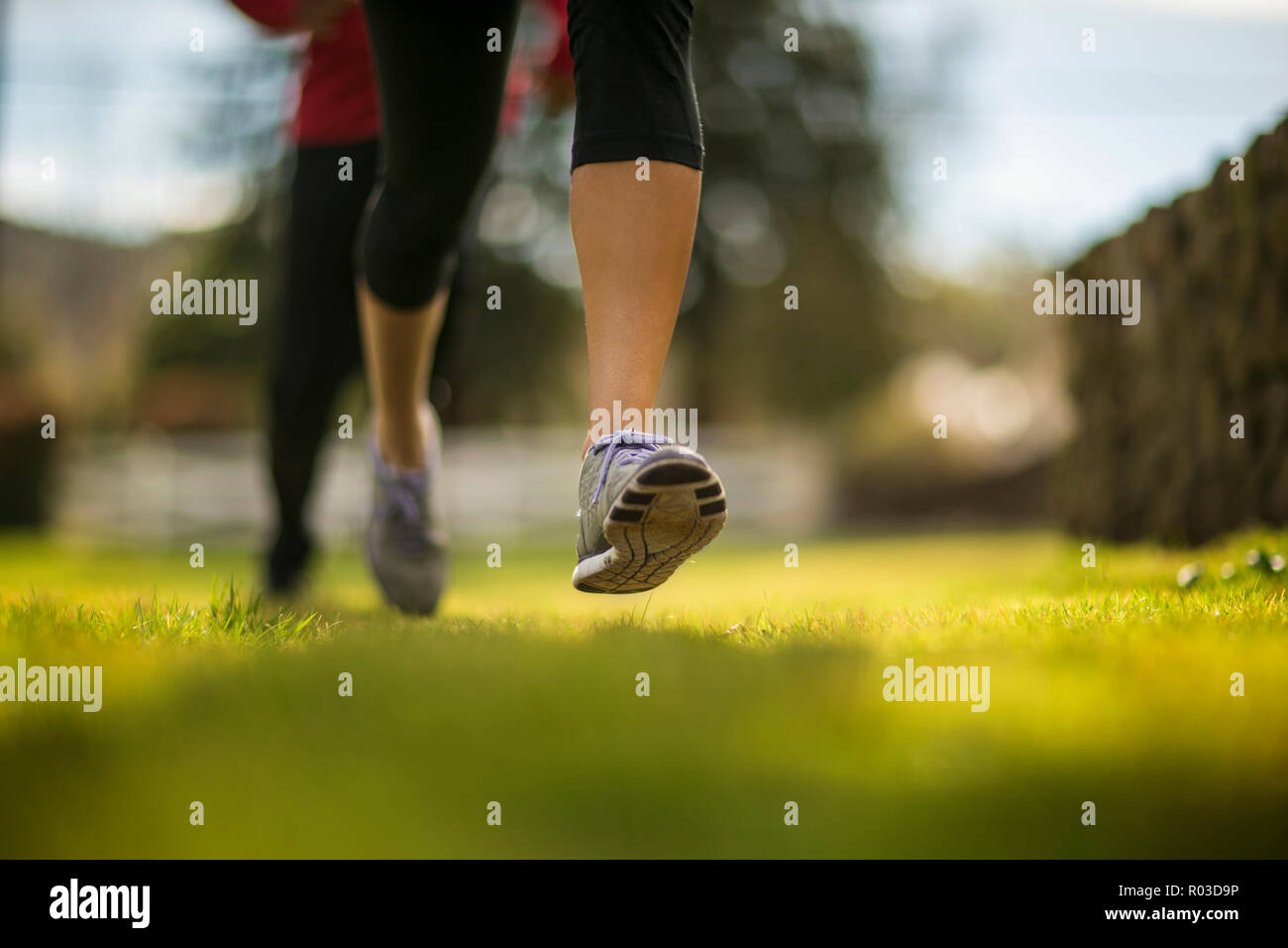 Young woman's feet run through a grassy park Stock Photo Alamy
