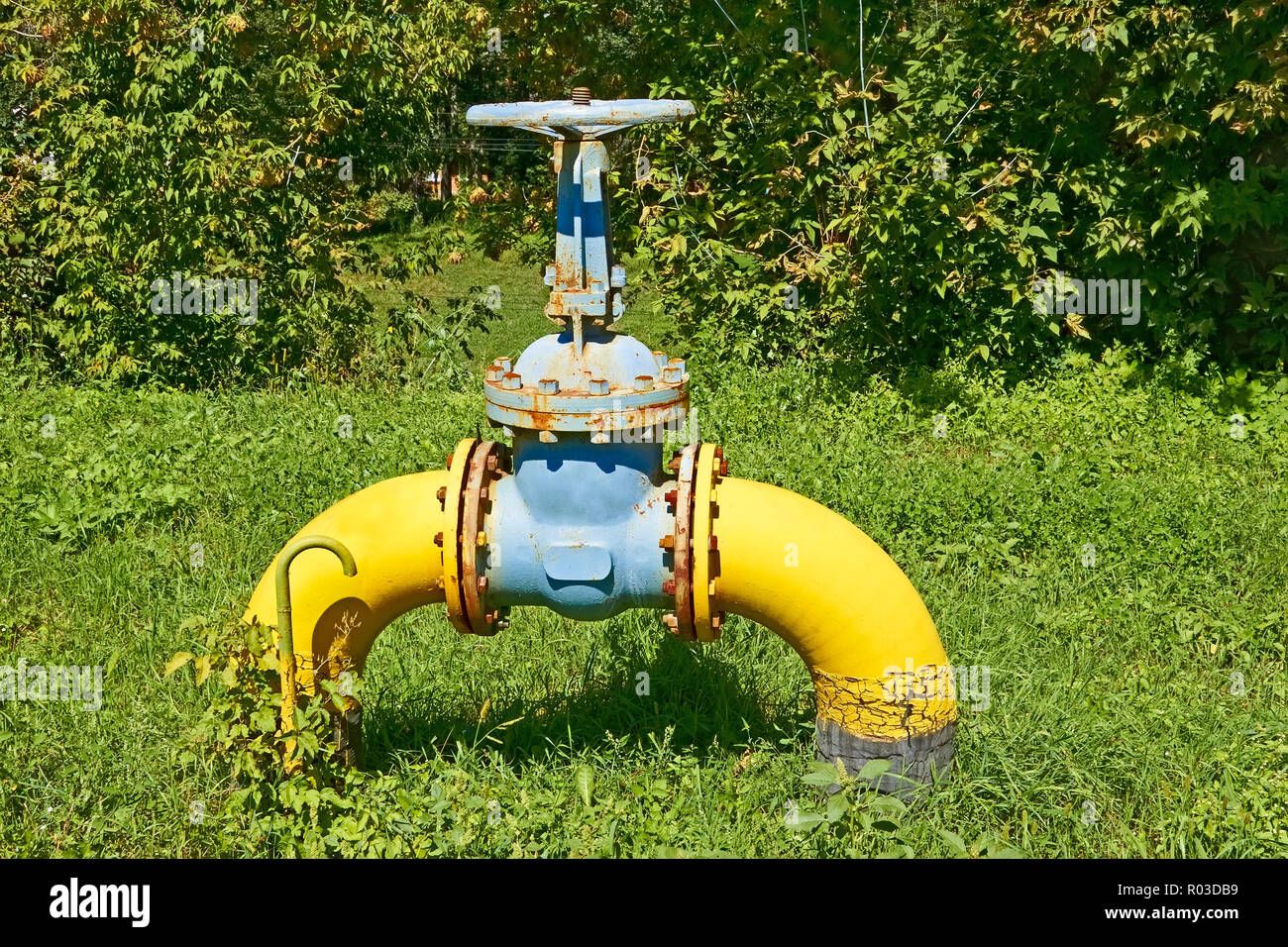 Large gas pipe with a valve and flanges above the ground on against the nature background Stock