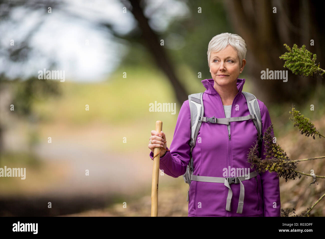 Portrait of a mature woman enjoying a peaceful hike along a forest trail. Stock Photo