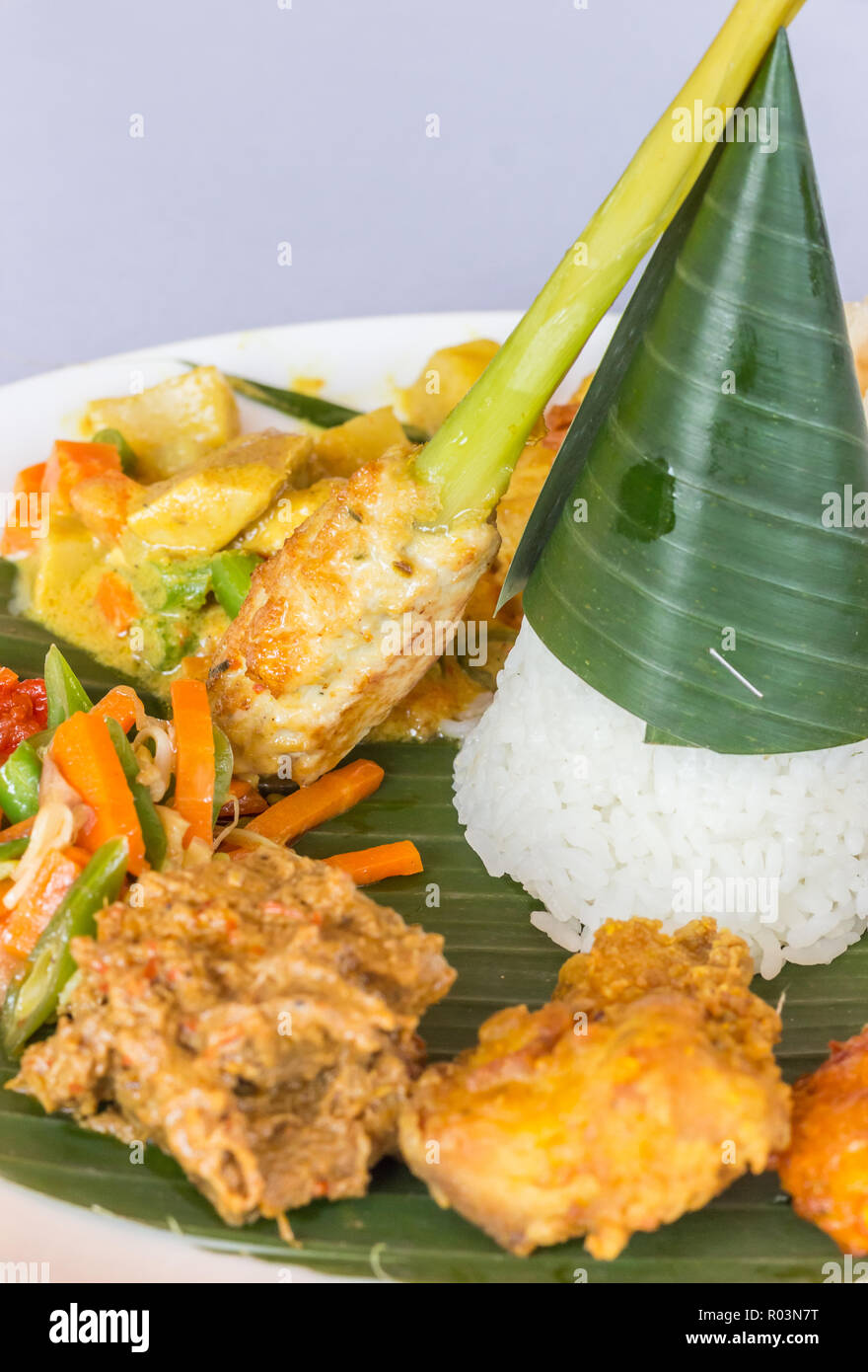 Nasi Campur Bali with tempeh, chicken and vegetables, served on a banana leaf Stock Photo