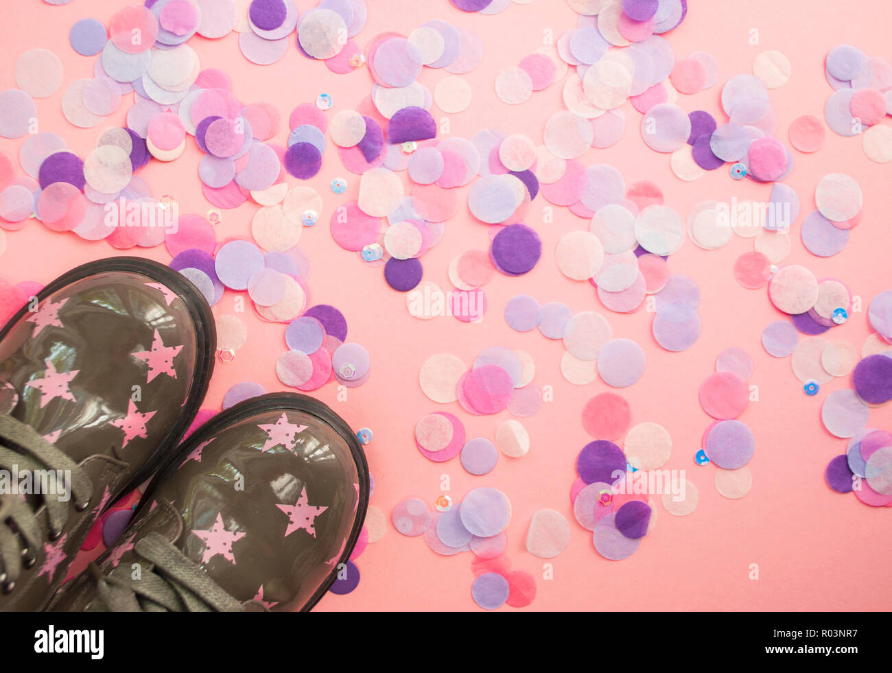Cute child's green color shoes with star print on pink background with colorful confetti. Stock Photo
