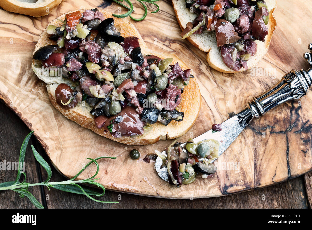 Homemade mixed Olive Tapenade made with garlic, capers, olive oil, Kalamata, black and green olives spread over toasted bread. Image shot from overhea Stock Photo
