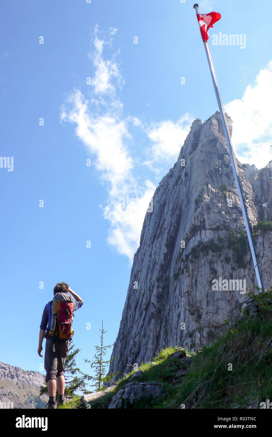 rock climber standing next to a flagpole with the Swiss flag as he