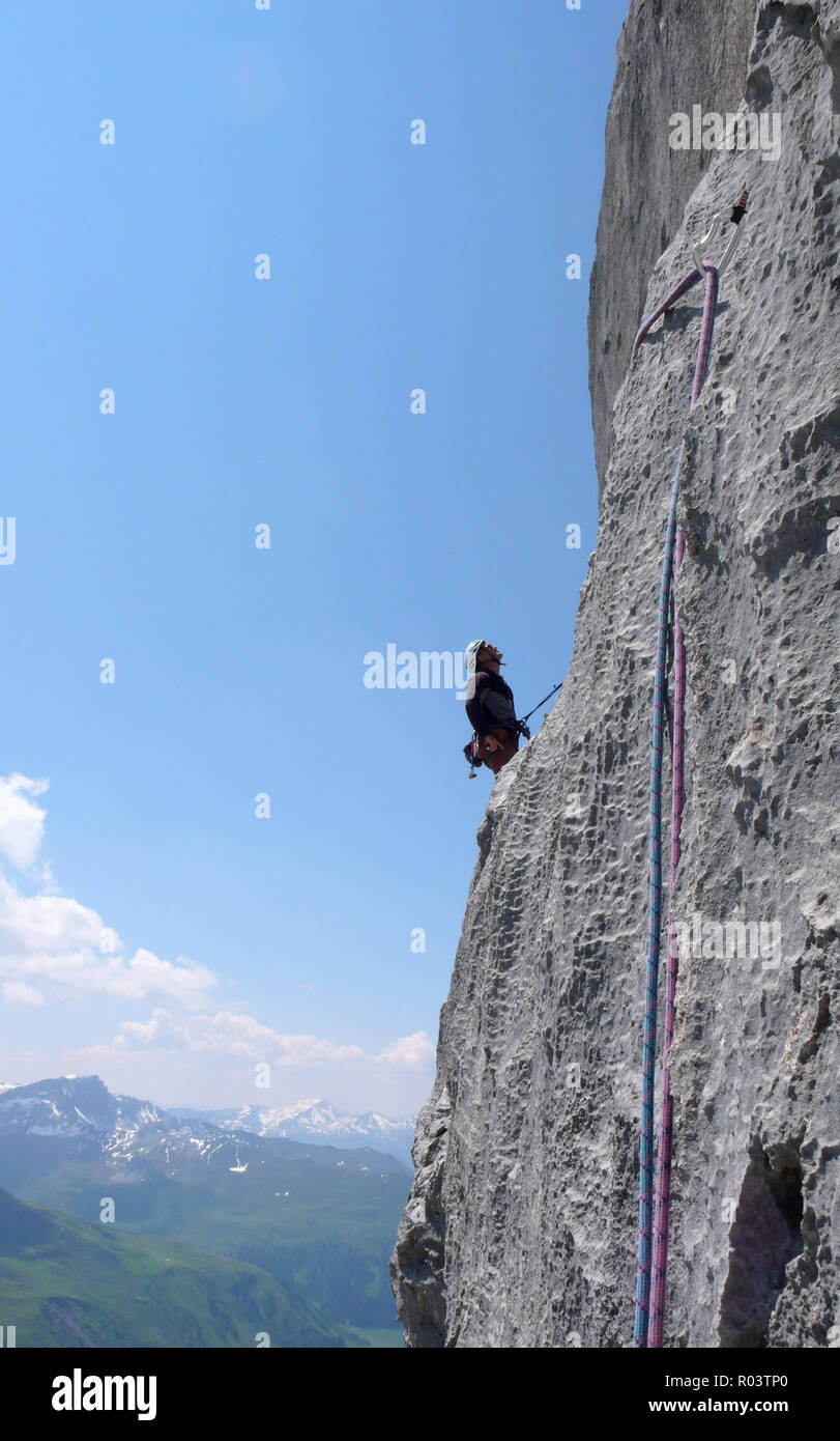 mountain guide rock climbing in the Alps of Switzerland in the Raetikon region near Klosters on a beautiful summer day Stock Photo