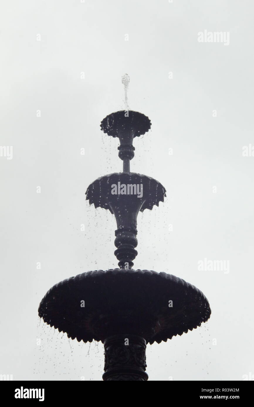 Three-tiered water fountain against overcast backdrop Stock Photo