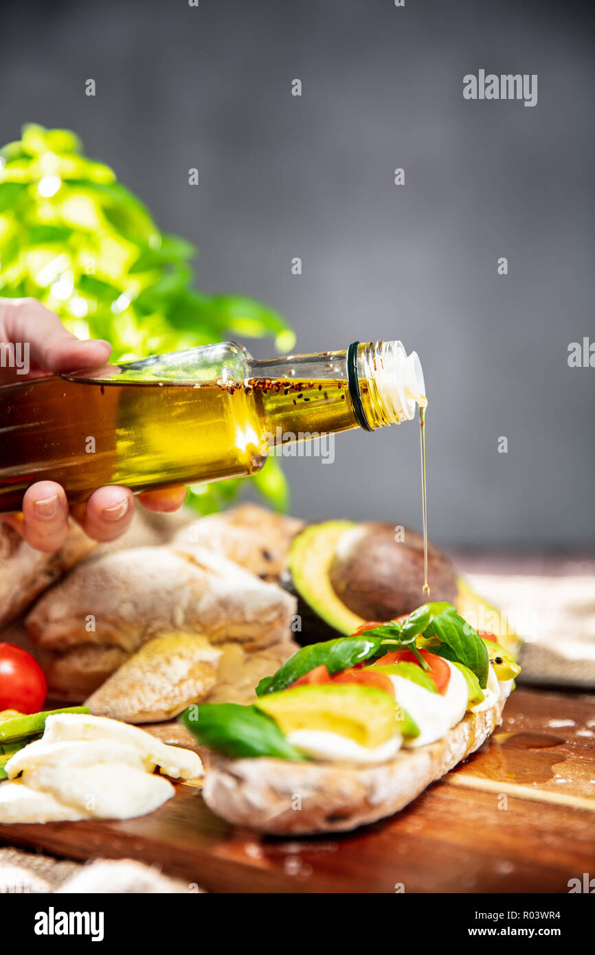 Hand Is Pouring Basil S Olive Oil On The Sandwich Made Of Ciabatta Bread Tomatoes Avocado Mozzarella And Fresh Basil Vertical Orientation Of Photo Stock Photo Alamy
