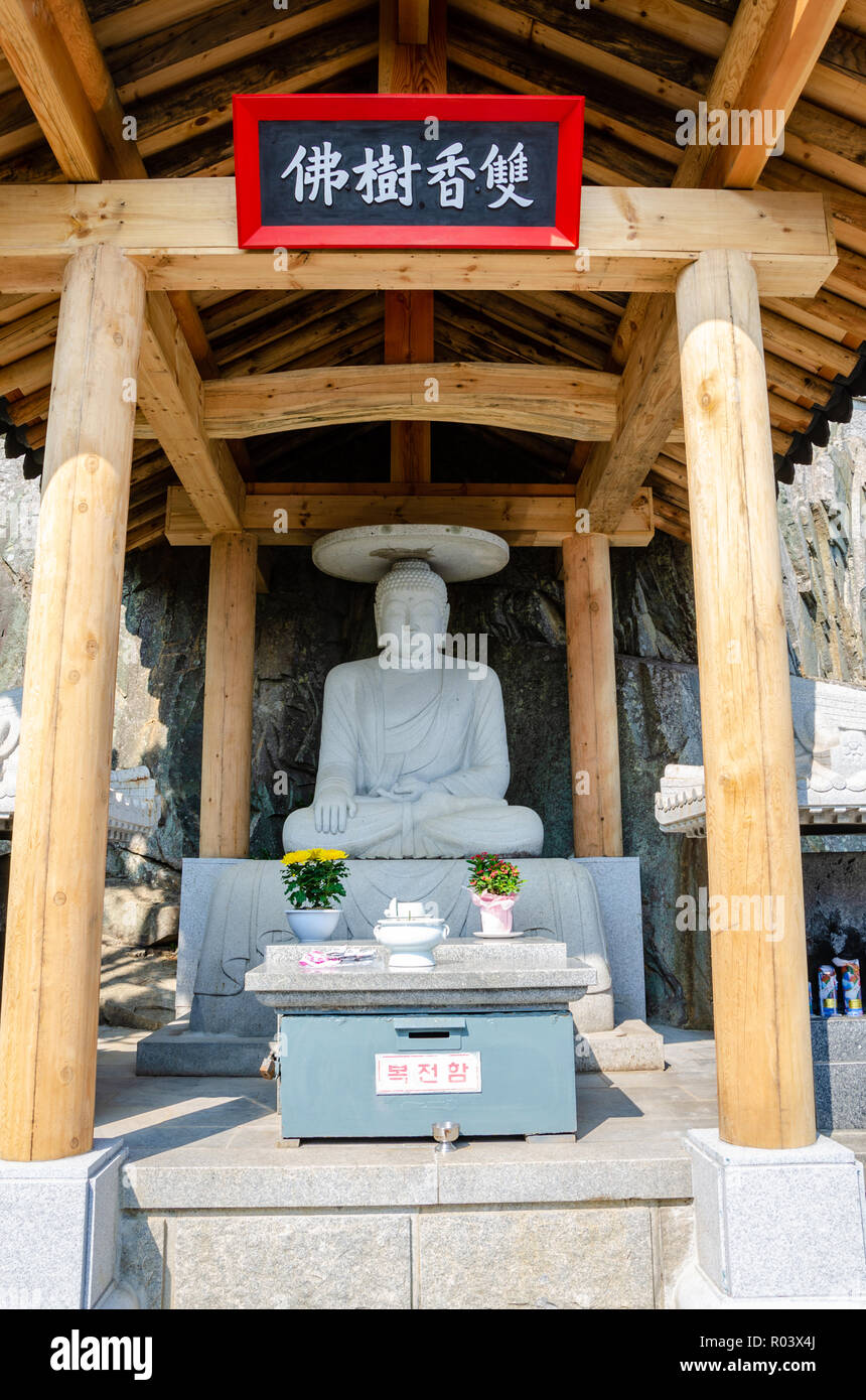 A shrine at the Haedong Yonggungsa Temple in Busan, South Korea featuring a sculpture of a seated Buddha. Stock Photo