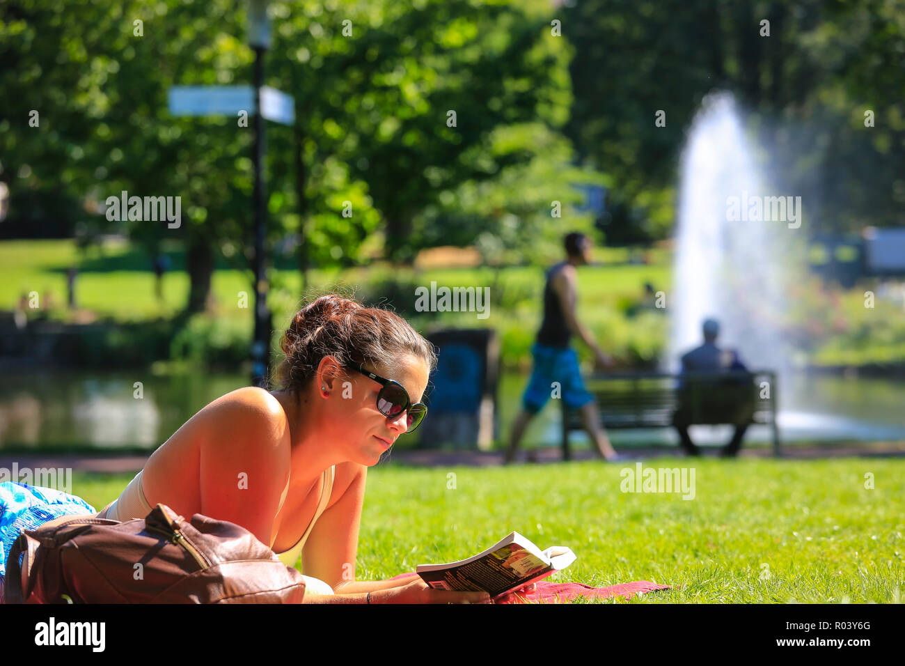 Essen, Germany, Ruhr area, city garden, young woman lies on the meadow and reads in a book Stock Photo