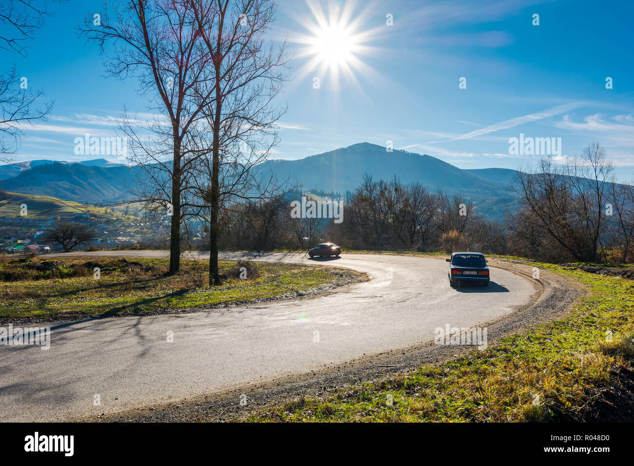 Volovets, Ukraine - NOV 16, 2017: serpentine in beautiful mountainous countryside. sunny november day. tall leafless trees along the road. village dow Stock Photo